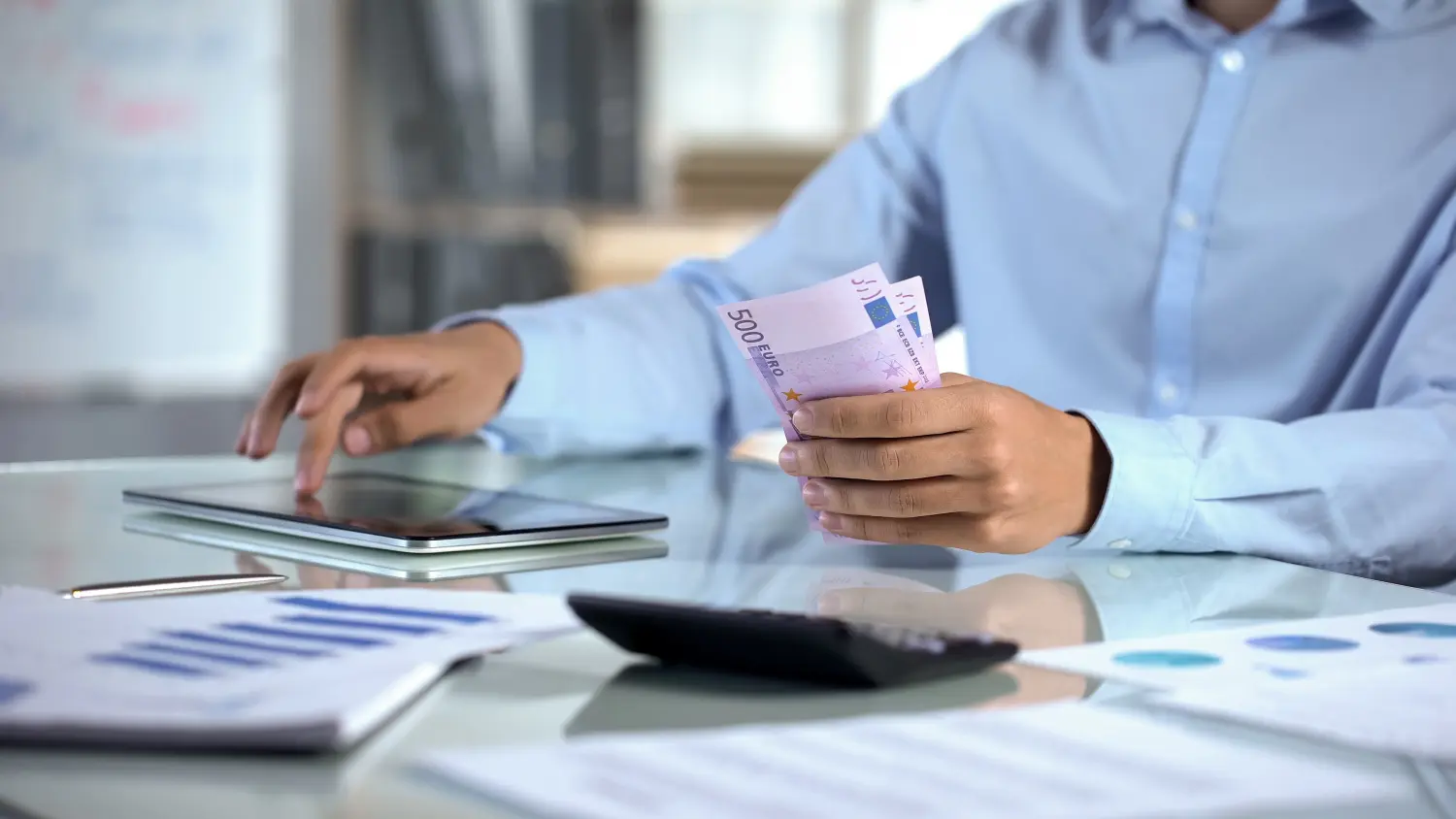 Geschäftsmann zählt Euro und plant das Unternehmensbudget mit einer Tablet-Anwendung